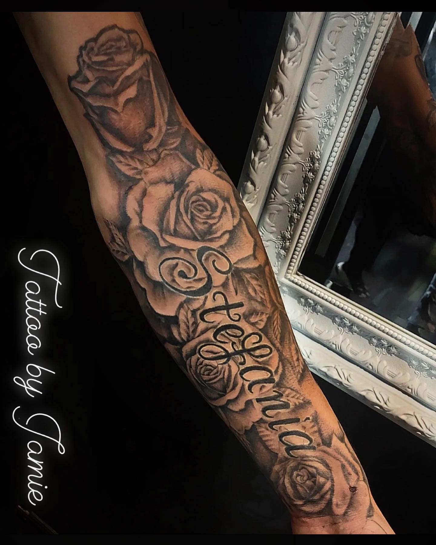 Black and grey roses with script lettering tattooed on a forearm by Jamie at Raro Tattoo